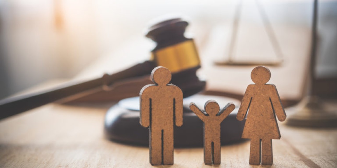 Image of a family represented by cardboard cutouts standing in front of a judge's mallet