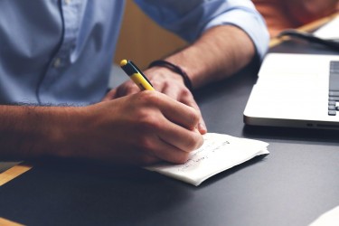 Person writing in front of a laptop